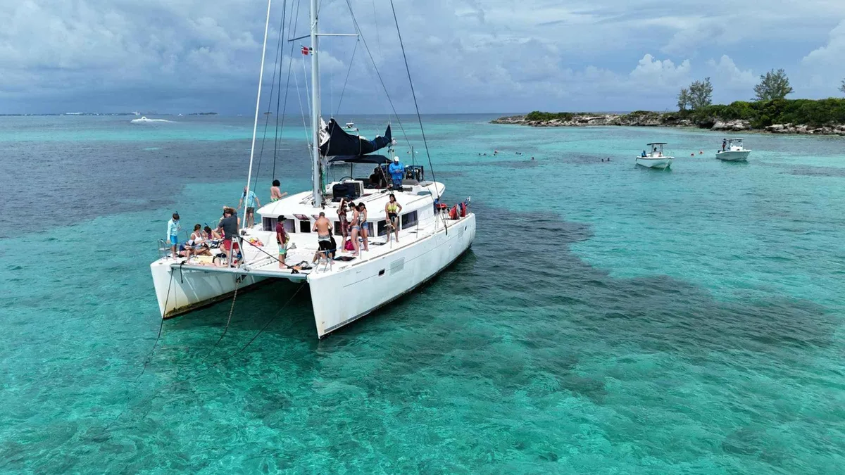 Catamaran moored off the sand where guests meet the pigs on a full-day swimming with pigs Nassau cruise, Bahamas